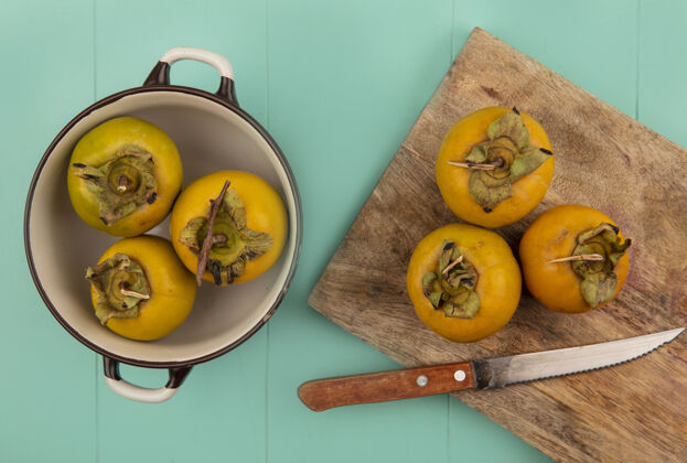 视图橙色柿子水果的顶视图在一个木制的厨房板上 在蓝色的木桌上 用刀在一个碗上切柿子水果厨房刀新鲜