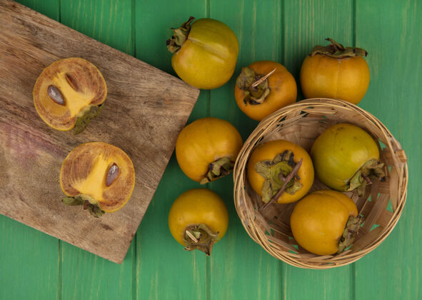 水果新鲜柿子水果在木制厨房板上的俯视图 柿子水果放在绿色木桌上的水桶上柿子木板景观