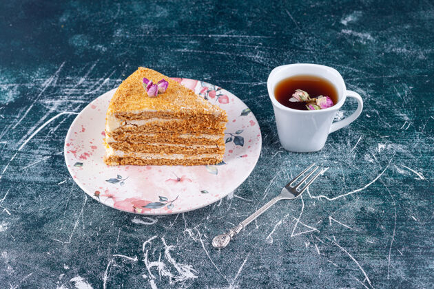 派一块蜂蜜蛋糕 用勺子和一杯茶放在五颜六色的表面上饼干分层烘焙