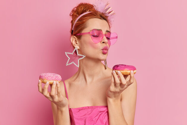 女孩图为时尚红发迷人的欧洲女人双唇紧闭手持两个开胃甜甜圈想吃甜点饮食嘴唇糕点
