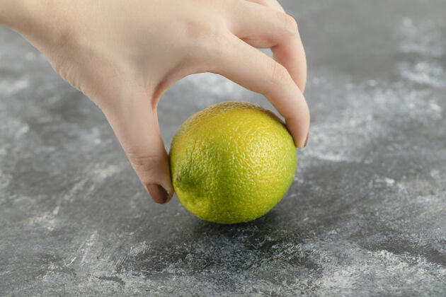 新鲜水果女人手里拿着一个新鲜的绿色柠檬水果热带食物