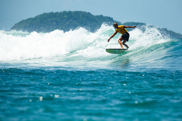 印度尼西亚在蓝色波浪上冲浪动作海洋冲浪者