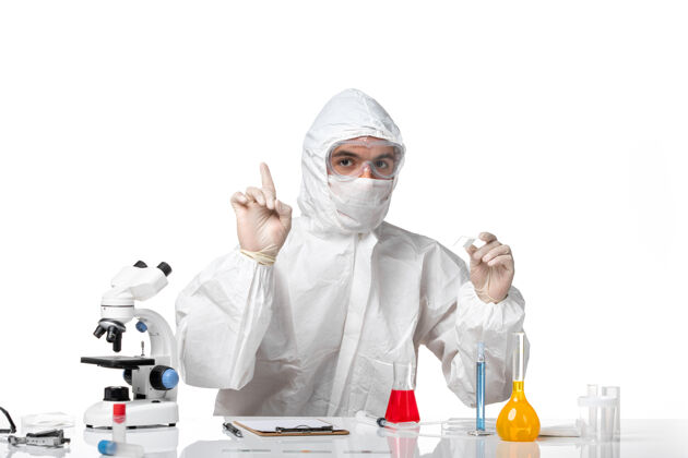 面罩正面图：男医生穿着防护服 戴着面罩 因为科维德在白色办公桌上用溶液工作防护办公桌工作