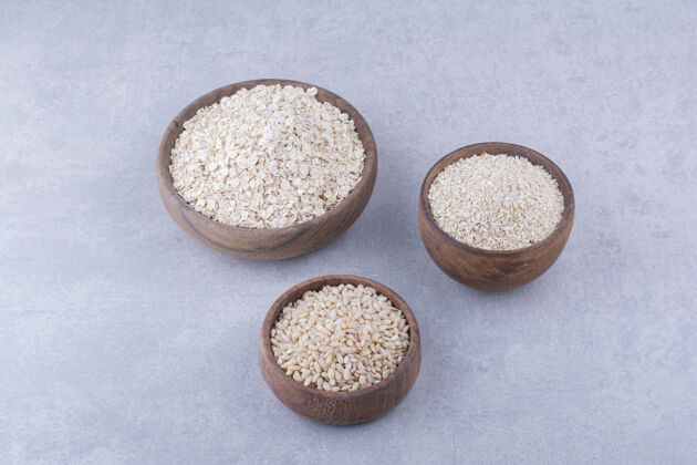 薄片在大理石表面放满米饭 燕麦和燕麦片的木碗碗燕麦片健康