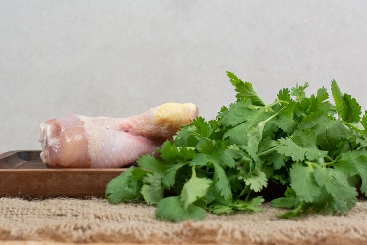 未煮熟的生鸡腿配青菜放在木砧板上未经料理的好吃的食物