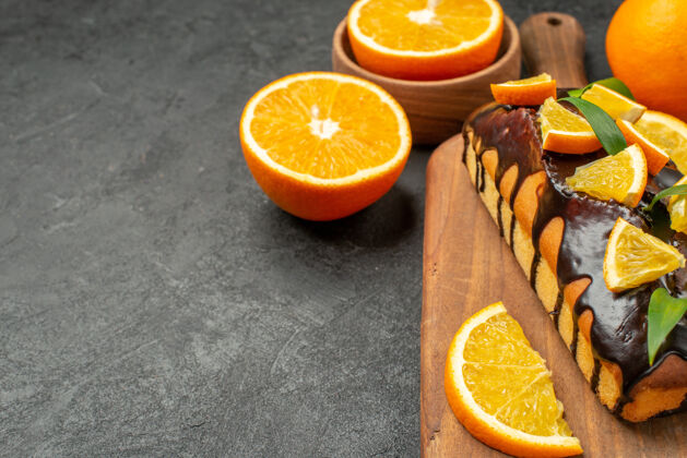 可食用水果侧视图美味的蛋糕整体和削减在切菜板上的黑色桌子上的桔子甜橙果汁新鲜