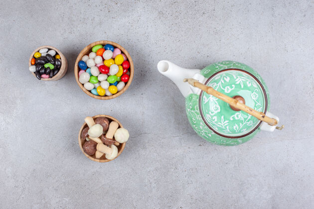 营养在大理石背景上华丽的茶壶旁边放着几碗糖果和蘑菇巧克力高质量的照片茶巧克力风味