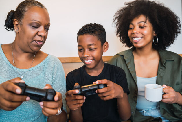 祖母非洲裔美国儿童的肖像教祖母和母亲如何使用操纵杆玩电子游戏操纵杆三三代