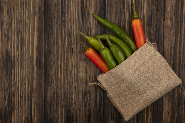 顶部彩色和新鲜辣椒上的麻布袋在木制背景与复制空间顶视图美食复制膳食