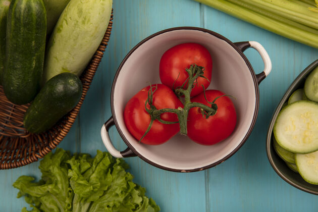 健康有机西红柿和西葫芦放在碗里 黄瓜放在桶里 生菜和芹菜放在蓝色的木制背景上碗观点顶部