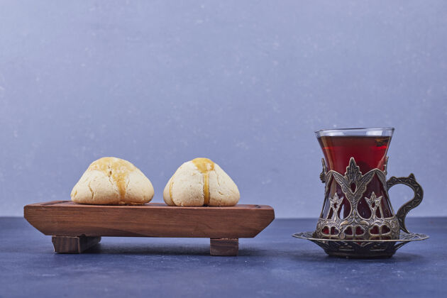 香草在一个木制盘子里放上黄油饼干和一杯茶高质量的照片烹饪精致厨房