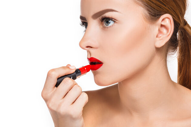 年轻美丽的女性唇妆和白色上的红色发油化妆师的工作过程女性粉应用