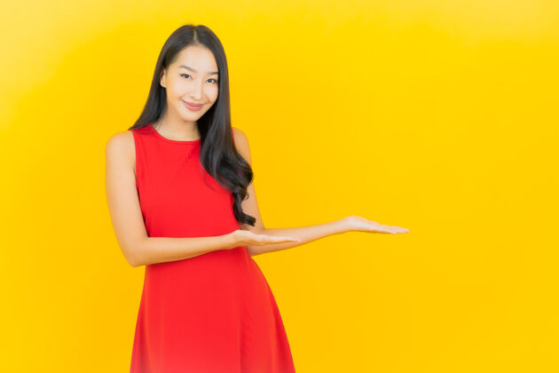 欢乐肖像美丽的亚洲年轻女子穿着红色连衣裙微笑着行动在黄色的墙上休闲微笑展示