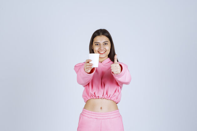 喜欢穿着粉色睡衣的女孩捧着咖啡杯 享受着咖啡的味道休闲女性姿势