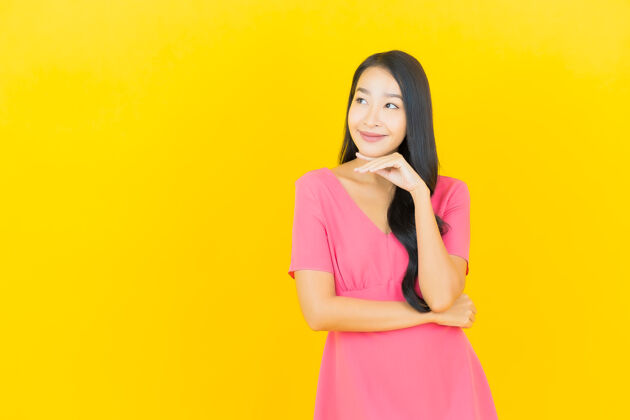 美丽黄色墙壁上 美丽的亚洲年轻女子身着粉色连衣裙微笑的画像亚洲人黑发光泽