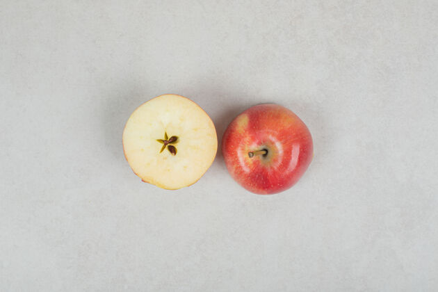 苹果整个和半个红苹果切在灰色的表面上整个有机美味