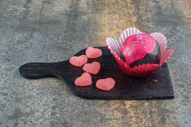 小吃巧克力饼干和粉红色釉面和糖果在木板上美味糕点饼干