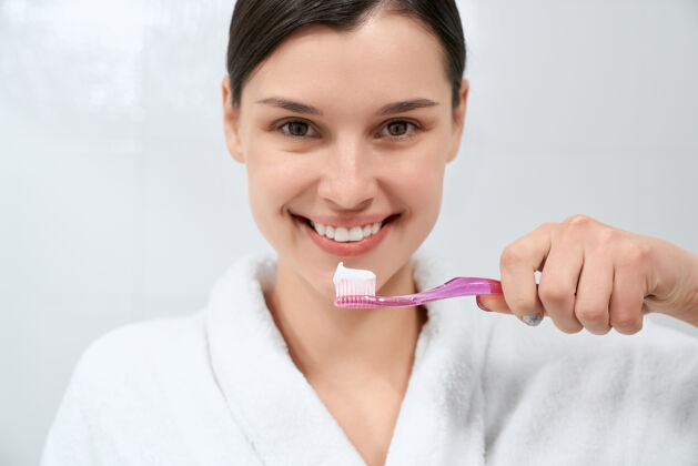 牙齿洗完澡后穿着白色长袍拿着牙刷的女人诊所口腔女人