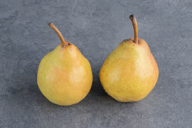 水果两个成熟的红黄色的梨果实被隔离在一个灰色的表面上黄梨健康美味