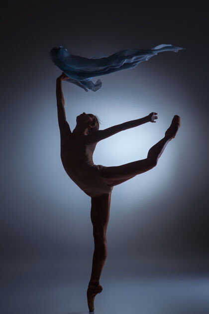 活跃美丽的芭蕾舞女演员在深蓝色背景下与面纱共舞的剪影经典优雅女孩