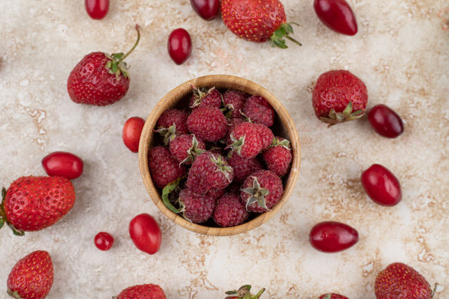 美味木盆中的覆盆子 臀部和草莓散落在大理石背景上高品质照片饮食草莓覆盆子