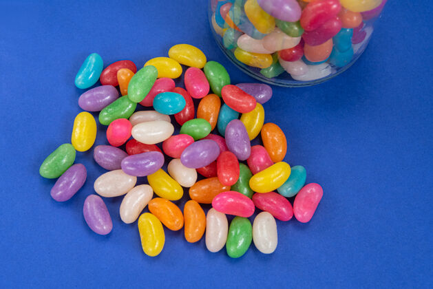 分类玻璃罐内蓝色表面上有几个果冻豆水果风味糖果