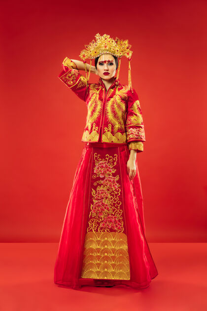 女性中国传统的优雅女子在摄影棚的红色背景美丽的女孩穿着民族服装中国新年 优雅 优雅 表演者 表演 舞蹈 女演员 服装的概念微笑中国人服饰