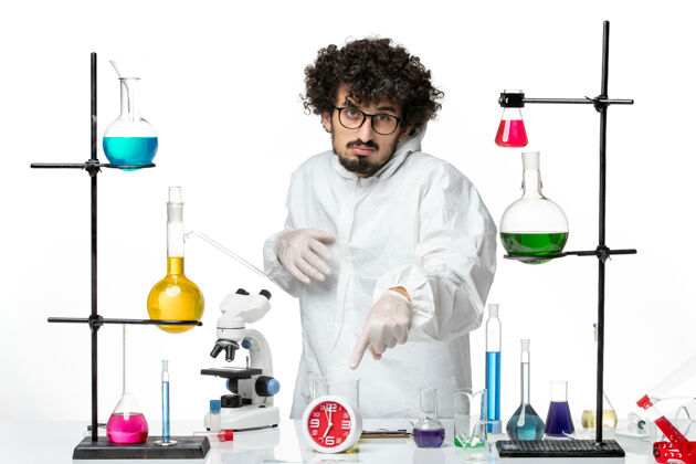 烧杯正面图年轻的男性科学家穿着白色的特别套装 在房间里用白色墙壁上的解决方案科学covid实验室大流行化学内部视图溶液