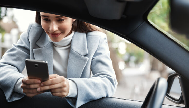 移动女商人靠在车窗上 在电话里发短信 笑得很开心商务司机微笑
