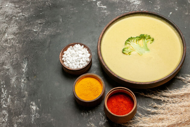 汤碗棕色碗中的奶油西兰花汤和灰色桌子上的不同香料的水平视图餐厅午餐蔬菜