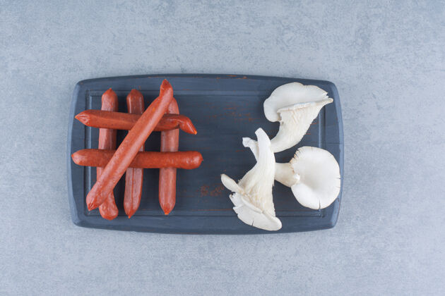 真菌牡蛎蘑菇和意大利腊肠在黑板上蘑菇牡蛎碗