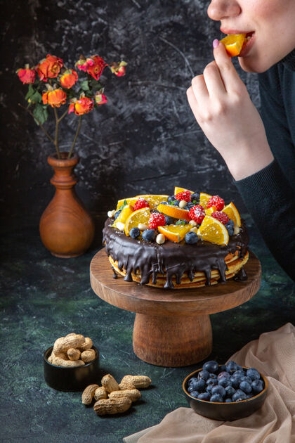 锅正面图美味的巧克力蛋糕得到装饰与新鲜水果的女性在黑暗的墙壁水果女糖