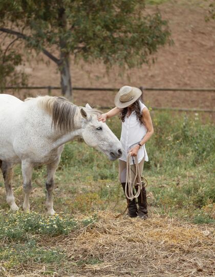 牛仔帽女农夫在抚摸她的马农场成熟老人