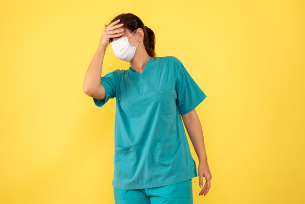 面具正面图黄色背景上穿着医用衬衫 戴着头痛面具的女医生人病毒肖像