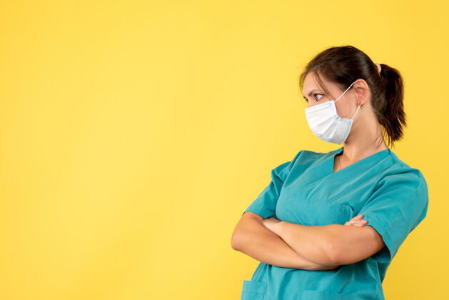 肖像正面图黄色背景上穿着医用衬衫和无菌口罩的女医生健康脸成人