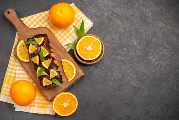 深色在黑暗的桌子上俯瞰着松软的蛋糕和切好的带叶子的橙子甜橙健康饮食