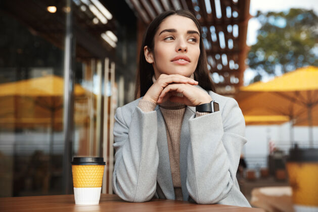 优雅漂亮的年轻女子穿着外套 戴着智能手表在咖啡馆里等着放松人外套