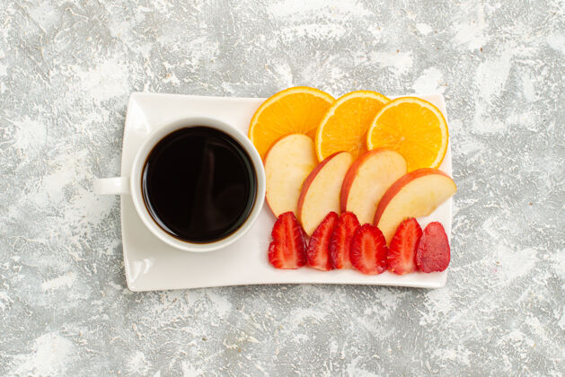 茶俯瞰一杯咖啡 配切片苹果 橙子和草莓 背景为白色水果 成熟 新鲜 醇厚早餐水果茶碟
