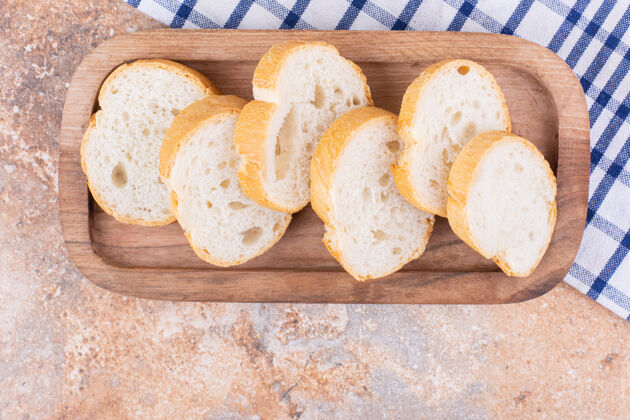 美味把法式面包片放在茶巾上的木板上 放在大理石上面团营养美味