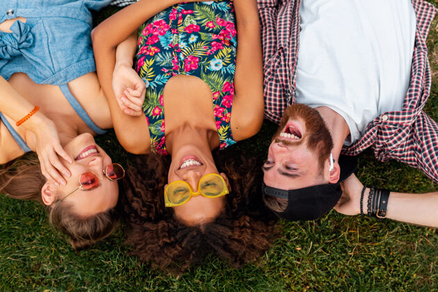 女人俯瞰五颜六色时尚快乐的年轻朋友们躺在公园的草地上 男女同乐在一起眼镜积极