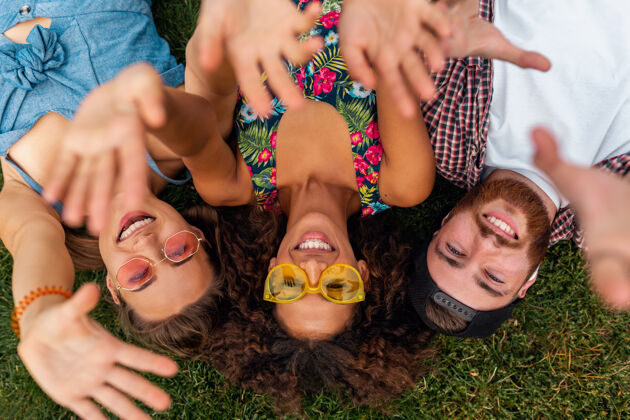 团结俯瞰五颜六色时尚快乐的年轻朋友们躺在公园的草地上 男女同乐友谊人年轻