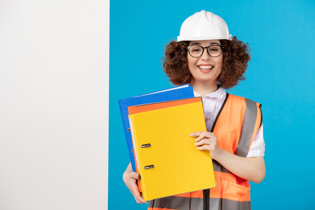 微笑蓝色墙上穿着制服的女建筑工人的正视图笔记本电脑专业人