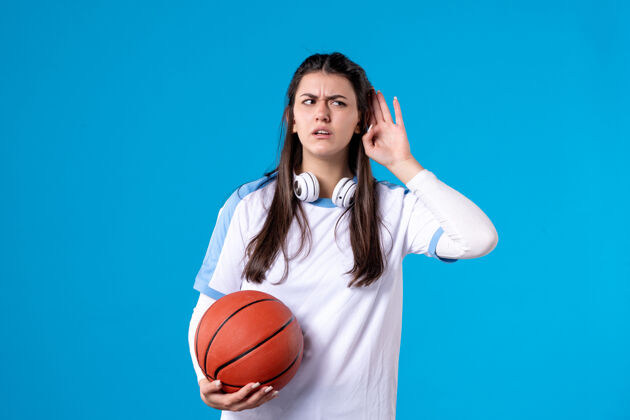 青年正面图：蓝色墙上挂着篮球的年轻女子成人篮球年轻女性