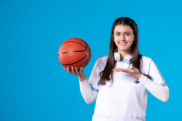 蓝色正面图：蓝色墙上挂着篮球的年轻女子女人人展示
