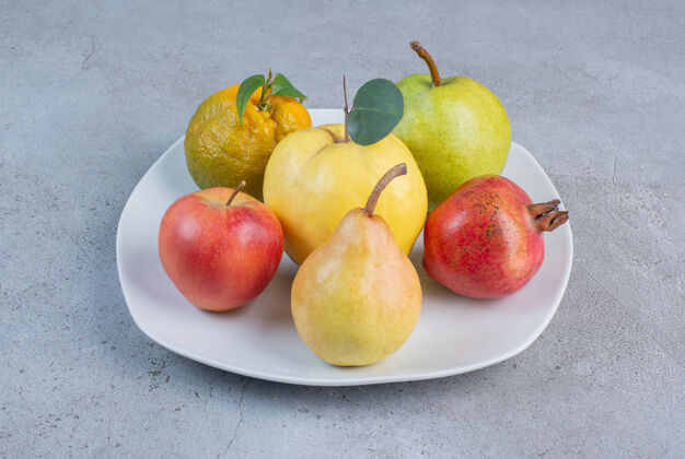 木瓜把石榴 梨 橘子 木瓜和苹果放在大理石背景的盘子里天然梨美味