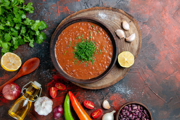 食物番茄汤配一束绿色的油瓶大蒜和勺子放在五颜六色的桌子上胡椒蔬菜油
