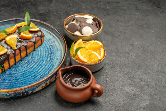 锅半张美味的蛋糕 用橘子和巧克力装饰 还有其他饼干放在黑桌子上巧克力容器香料