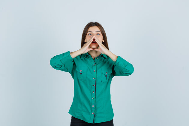 女人照片中的年轻女士手拉手靠近嘴边 穿着绿色衬衫讲着秘密 看着好奇的前景色思想女性秘密