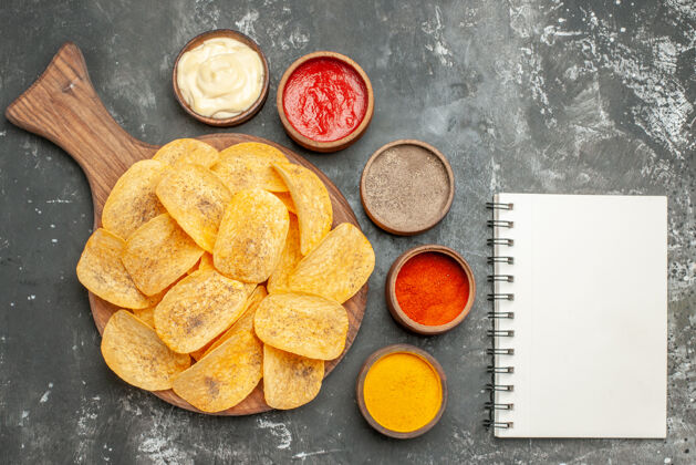 烘焙自制薯片 香料和蛋黄酱 切菜板上放番茄酱 灰色桌子上放笔记本番茄酱自制薯条蛋黄酱