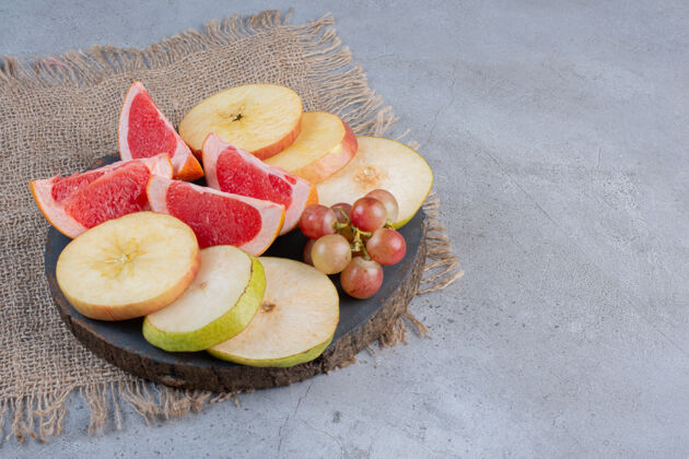 天然在大理石背景的木板上放上一小串葡萄和梨子片美味健康片